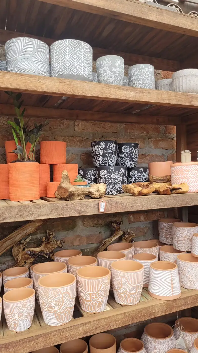 Prateleiras de madeira com vasos de cerâmica branca e terracota de vários tamanhos, organizados por linha