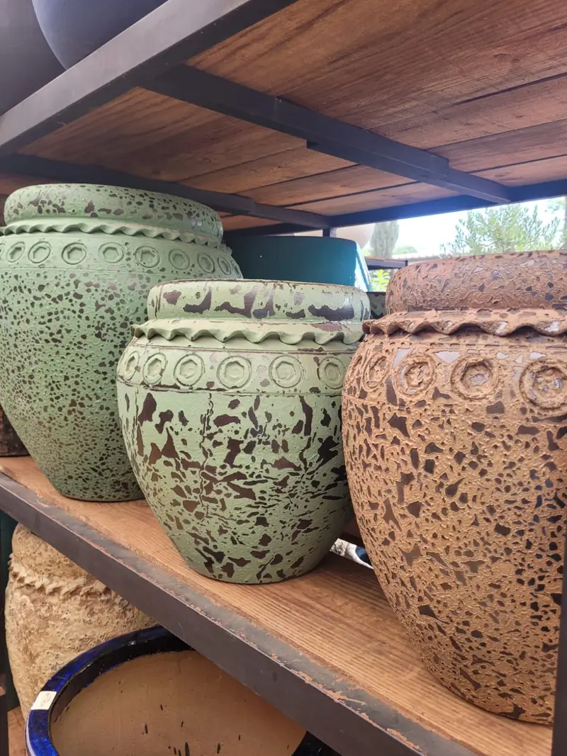 Vasos de cerâmica esmaltada em verde e terracota craquelada sobre prateleira de madeira